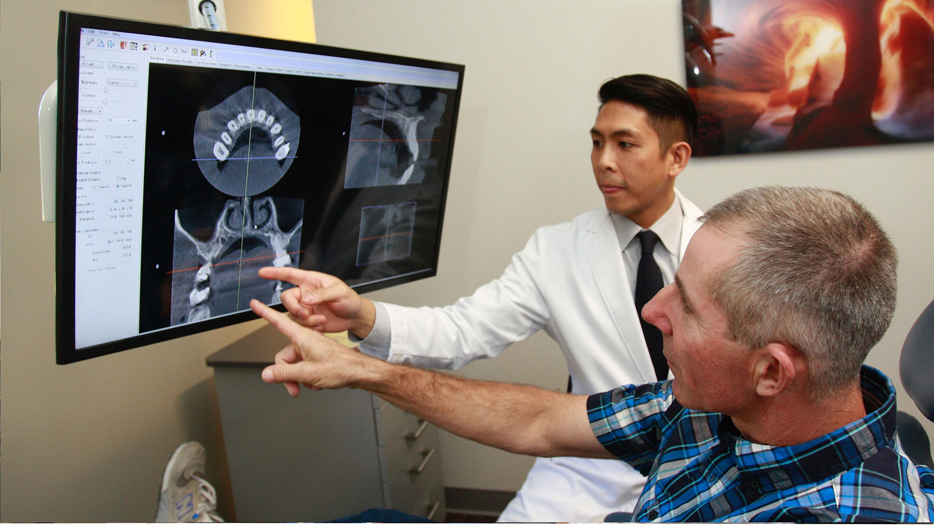 A medical professional is presenting a 3D model of a human body to a patient, with the patient pointing at a specific area on the model.