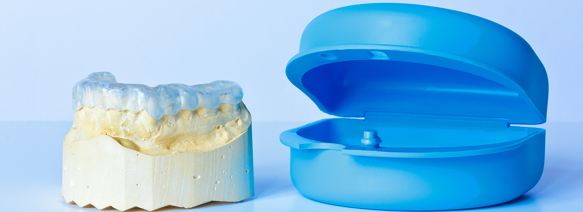 A side-by-side comparison of a dental implant and a blue plastic model, both placed on a white surface.