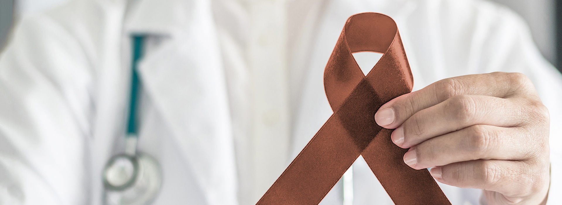 The image shows a medical professional holding a red ribbon, which is commonly associated with awareness for various health causes.