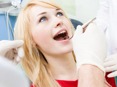 The image shows a young woman receiving dental treatment, with a dental professional using a drill on her tooth.