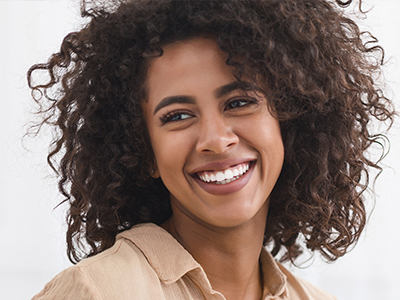 The image features a woman with curly hair and a radiant smile, looking directly at the camera.